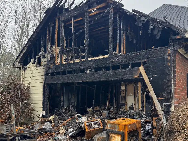 Burned-out house with severe fire damage and debris.
