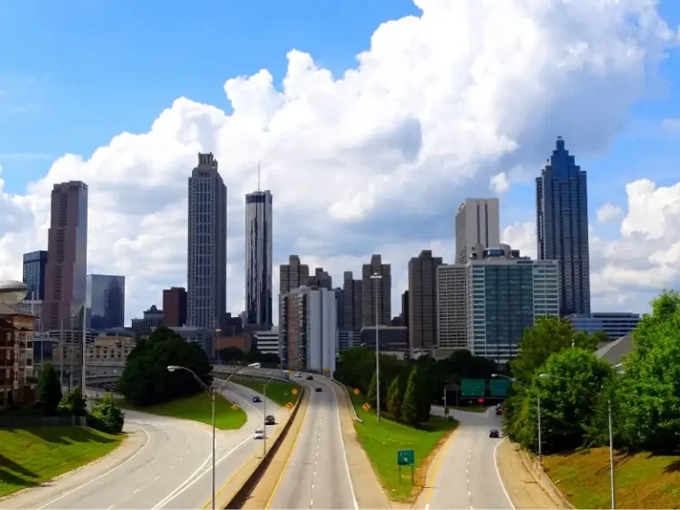 City skyline with a highway leading toward downtown under large clouds.