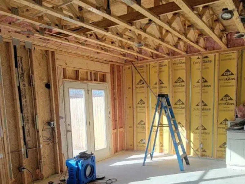 Unfinished room under construction with exposed framing and a blue ladder.