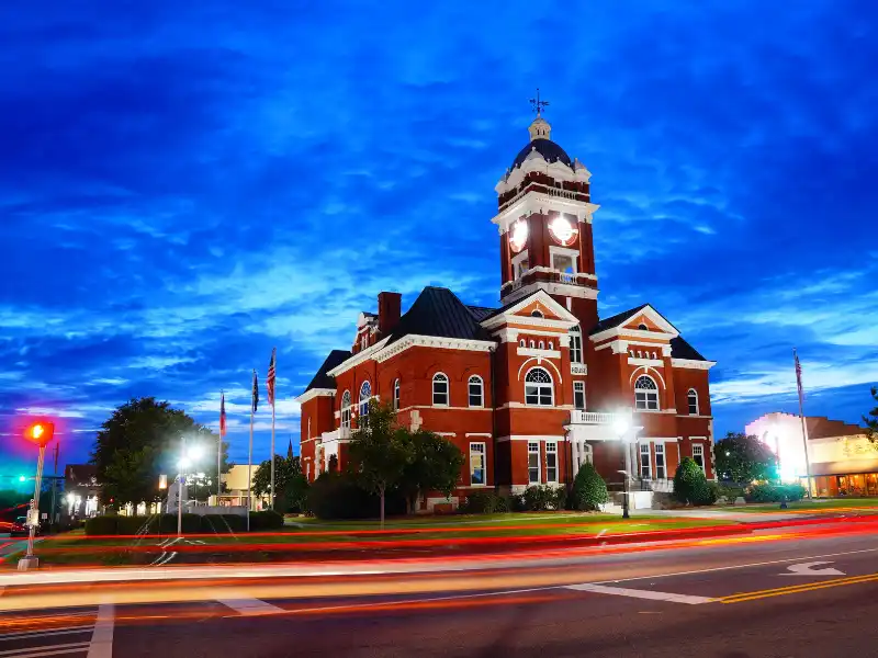 Historic red-brick courthouse with a clock tower at dusk.