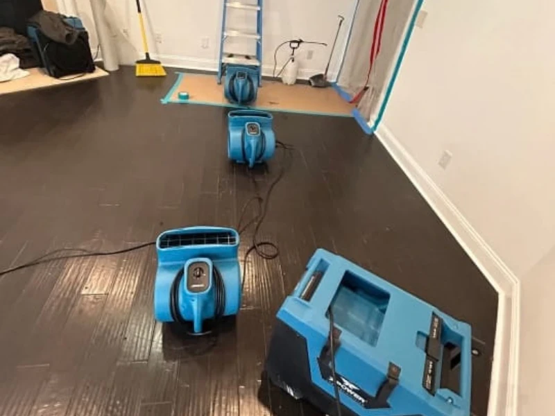 Blue floor sanders on a dark hardwood floor in a room under renovation.